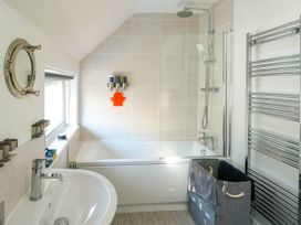 A bathroom with a bathtub shower sink towel rack and storage basket at Annedd Wen in Rhosneigr