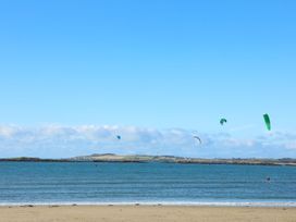 A beach with the sea and kite surfers in the water at Annedd Wen in Rhosneigr