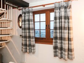 A window with curtains and a spiral staircase at Sammy Hakes Cottage