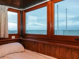 A bedroom with a bed and windows at Sammy Hakes Cottage