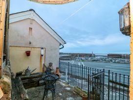 An outdoor area with a bench and chairs by a road at Sammy Hakes Cottage