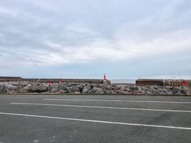 A view of a pier and lighthouse from a road at Sammy Hakes Cottage