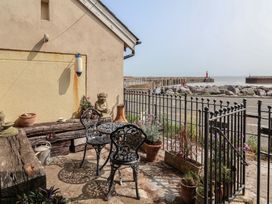 An outdoor patio with chairs and a table overlooking a pier at Sammy Hakes Cottage in Watchet