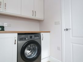 A laundry room with a washing machine and cabinets at St Marys in Penzance