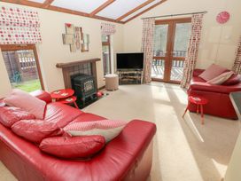 A living room with a red sofa and armchair at Riverside Lodge 3