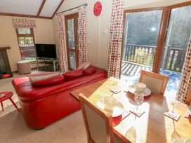 A living room with a television and dining area at Riverside Lodge 3