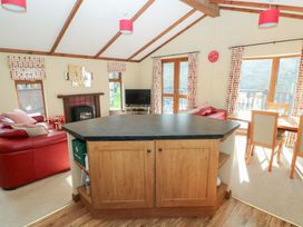 A living room with a kitchen island and television at Riverside Lodge 3