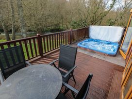A deck with a hot tub and outdoor furniture at Riverside Lodge 3