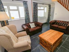 A living room with leather sofas and a wooden coffee table at Coach House Cottage 