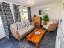 A sitting room with a sofa, chairs, and a table at Coach House Cottage
