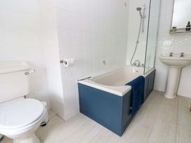 A bathroom with a bathtub, toilet, and sink at Coach House Cottage