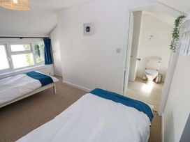 A bedroom with two beds and a bathroom door at Coach House Cottage