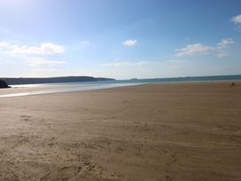 A beach with sand and ocean under a blue sky with a few people at the shoreline