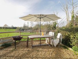 A table with an umbrella and chairs at Wiltshire Weavers Hut Sutton Benger near Christian Malford