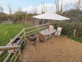An outdoor space with a table and chairs under an umbrella at Wiltshire Weavers Hut Sutton Benger near Christian Malford
