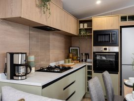 A kitchen with cabinets, gas stove, coffee maker, microwave, and refrigerator at Arlington 40 x 14 Two Bed