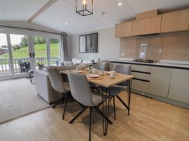 A living room with a dining table and kitchen units at The Pines 2 Bedrooms in Delamere