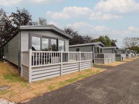 Exterior view of cabins with decks on a pathway at The Pines 2 Bedrooms Delamere