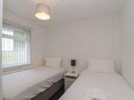 A bedroom with two single beds and a bedside table at Harcombe House Bungalow 25 in Chudleigh