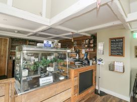 A cafe counter with a display case and menu board at Harcombe House Bungalow 25, Chudleigh