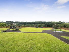 A playground with slides and swings in a green area at Harcombe House Bungalow – Pet Friendly with Wet Room, Chudleigh