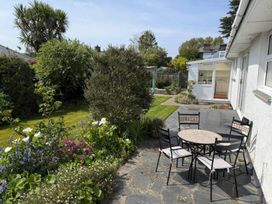 A garden with a table and chairs surrounded by flowers at 42 Little Trelyn, Rock