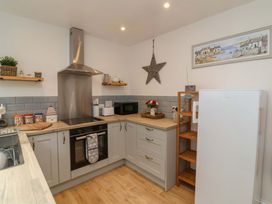 A kitchen with stove, oven, microwave, and refrigerator at Zide the Zea in Hele Bay, Ilfracombe