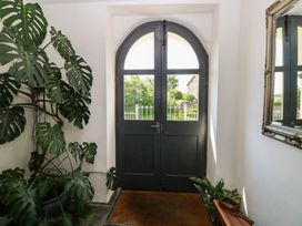 An entrance with a dark arched double door a large leafy plant a mirror on the wall and a small wooden bench at Zoar Chapel in Carew