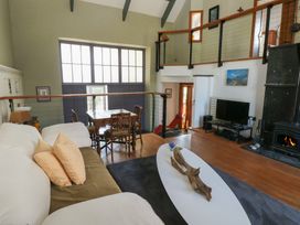 A living room with a white and green sofa a wooden dining table and chairs a television near a fireplace at Zoar Chapel in Carew