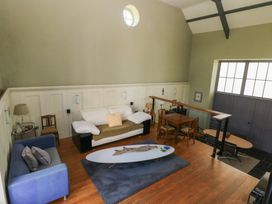 A two-level room with couches a coffee table a dining table and chairs a lamp and large windows at Zoar Chapel in Carew
