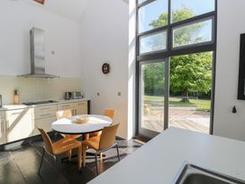 A kitchen with a round table and four orange chairs near large windows showing trees outside at Zoar Chapel in Carew