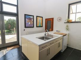 A kitchen with an island sink cabinet dishwasher wall clock and framed pictures at Zoar Chapel in Carew