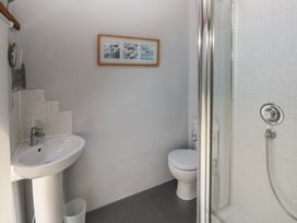 A bathroom with a pedestal sink a toilet a framed picture on the wall and a shower with glass door at Zoar Chapel in Carew