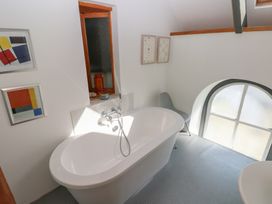 A bathroom with a freestanding bathtub a chair two framed pictures and a window at Zoar Chapel in Carew