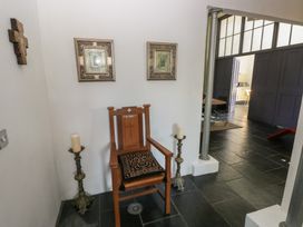 A wooden chair with a patterned cushion between two candlesticks and religious artwork on the wall at Zoar Chapel in Carew