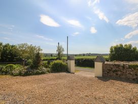 A gravel driveway with garden beds and an open gate leading to a road and fields at Zoar Chapel in Carew