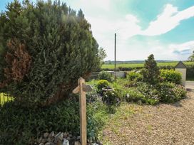 A garden with bushes flowers a bird bath and a wooden directional signpost at Zoar Chapel in Carew
