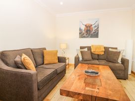 A living room with two brown sofas a wooden coffee table a lamp and a painting of a bull at Smiddy Bothy in Edzell
