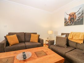 A living room with two brown sofas a wooden coffee table with a glass dish and remote controls a lamp on a side table and a painting of a bull on the wall at Smiddy Bothy in Edzell
