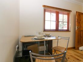 A small dining table set with two place settings and two chairs by a window with wooden blinds at Smiddy Bothy in Edzell