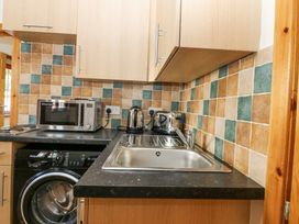 A kitchen corner with a sink microwave kettle toaster and washing machine at Smiddy Bothy in Edzell
