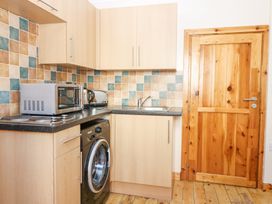A kitchen corner with a washing machine microwave kettle toaster sink and wooden door at Smiddy Bothy in Edzell
