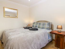 A bedroom with a double bed two side tables with lamps a mirror on the wall and folded towels on the bed at Smiddy Bothy in Edzell