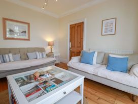 A living room with sofas, a coffee table, and a lamp at Harbour House in Looe