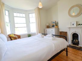 A bedroom with a bed and windows at Harbour House in Looe