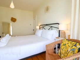 A bedroom with a bed and chair at Harbour House in Looe