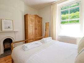 A bedroom with a bed and wooden wardrobe at Harbour House in Looe