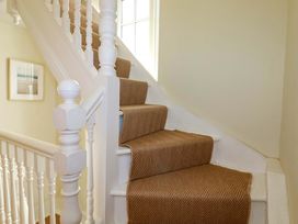 A staircase with carpet runner and handrail at Harbour House in Looe