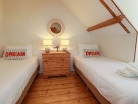 A bedroom with two beds and a wooden bedside table at Harbour House in Looe