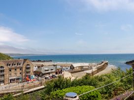 A beach with buildings and a pier at Harbour House in Looe
